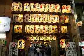 Farolillos de papel iluminados en la entrada de un templo de Kyoto