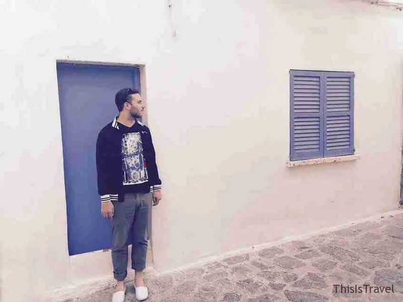 Viajero junto a una puerta azul en una calle encalada de Ibiza