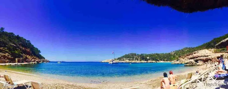 Cala de aguas turquesa con barcos fondeados, en Ibiza