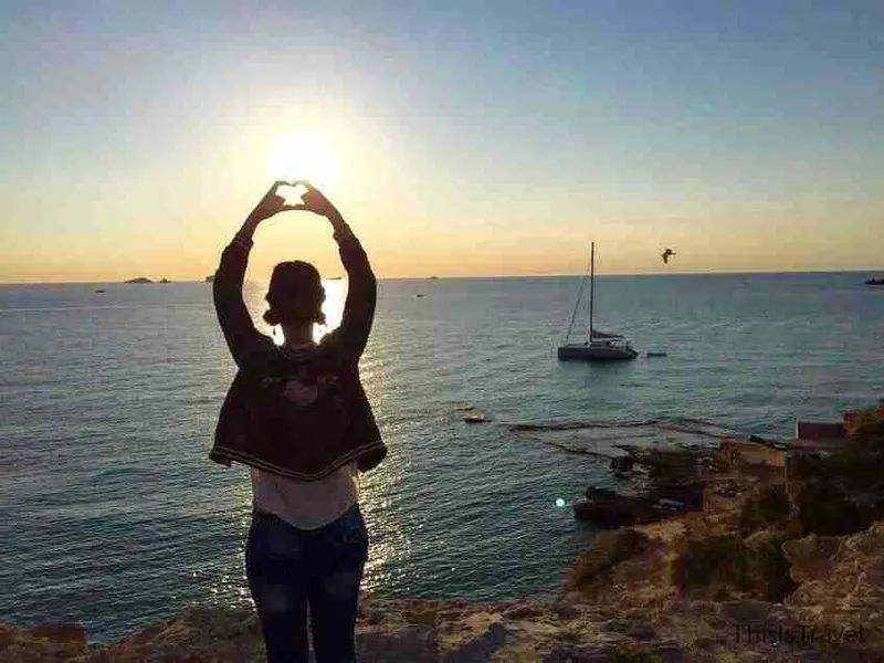 Silueta haciendo un corazón con las manos al atardecer frente al mar, en Ibiza