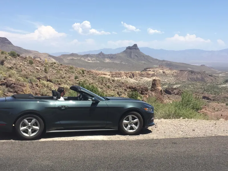 El Mustang descapotable del road trip en una carretera del desierto