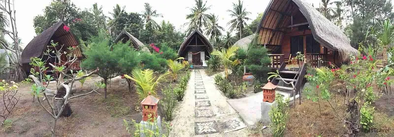 Camino de piedra entre palmeras hacia los bungalós de paja de Gili Air