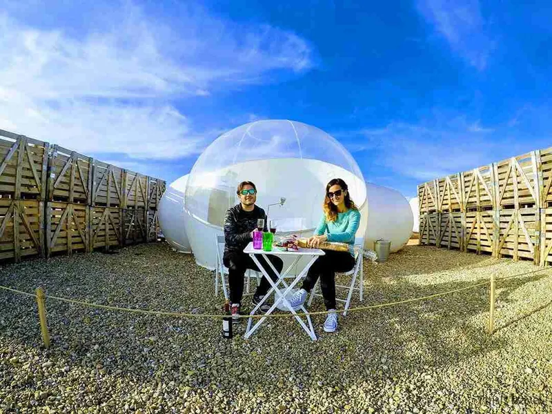 Dos viajeras en una mesa delante de la habitación burbuja del hotel Aire de Bardenas