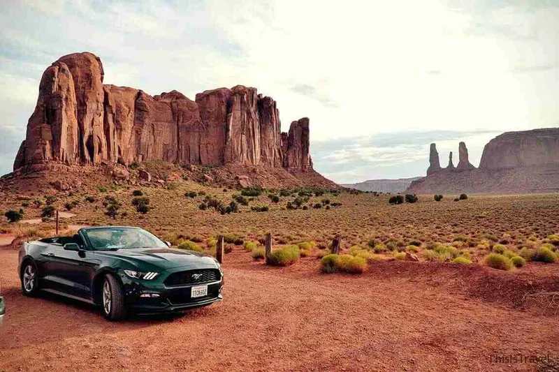 Descapotable aparcado ante las formaciones rojizas de Monument Valley