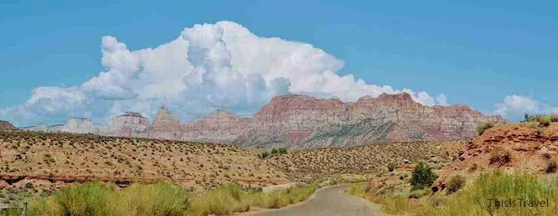 Carretera hacia Zion entre paredes de roca rojiza bajo un cielo de nubes