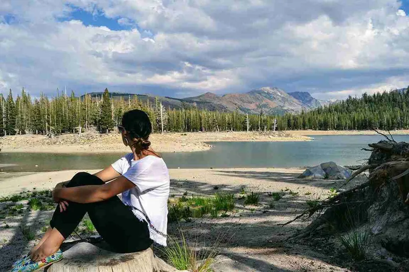 Viajera sentada en las rocas a la orilla de un lago de Mammoth Lakes