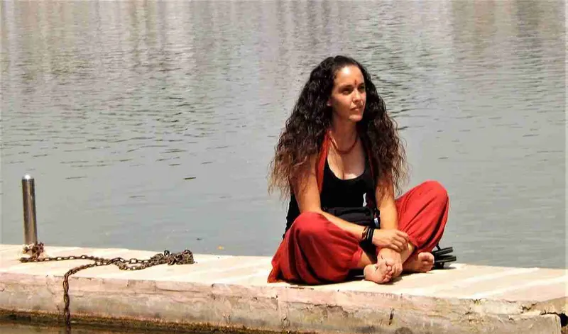 Viajera sentada con las piernas cruzadas junto al agua