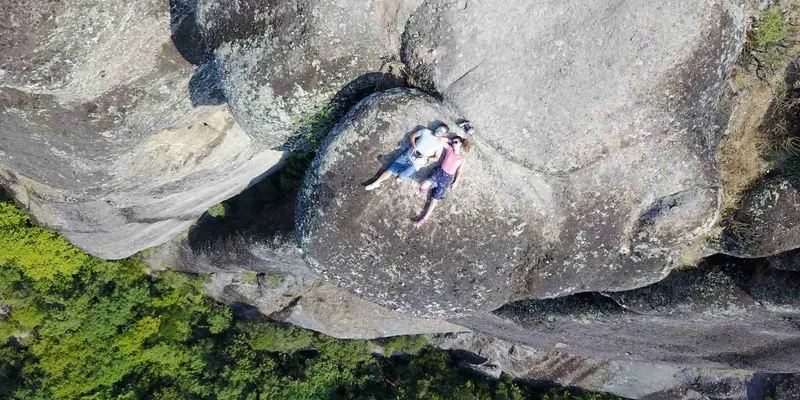 Vista aérea tomada con el dron de dos personas tumbadas sobre una roca