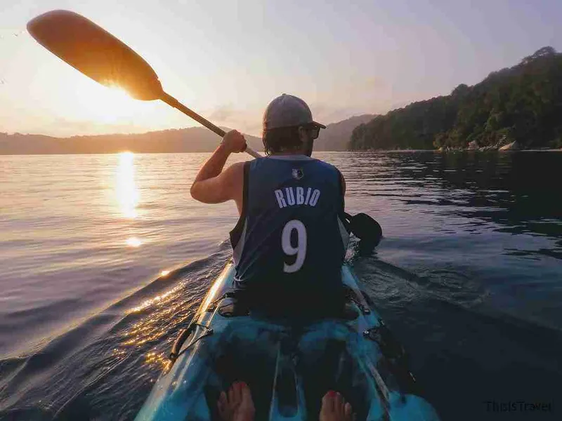 Remando en kayak al atardecer frente a la costa boscosa de las Perhentian