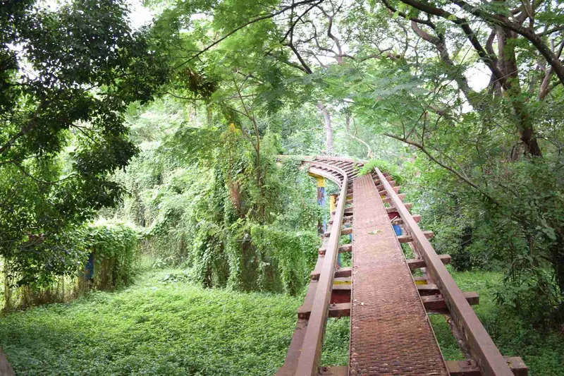 Raíles de la montaña rusa abandonada, tragados por la selva