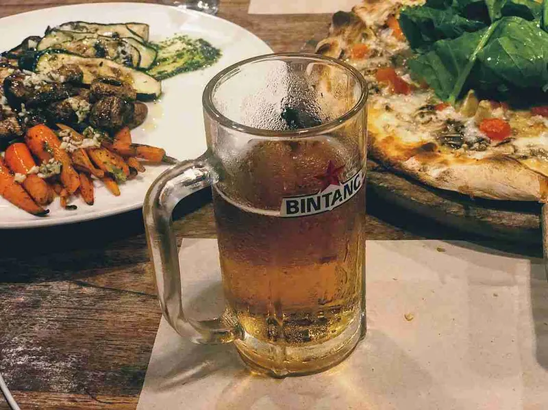Jarra de cerveza y pizza en la mesa de la Trattoria de Sanur