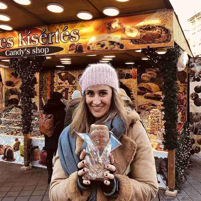Bebida caliente en la mano frente a un puesto del mercado navideño