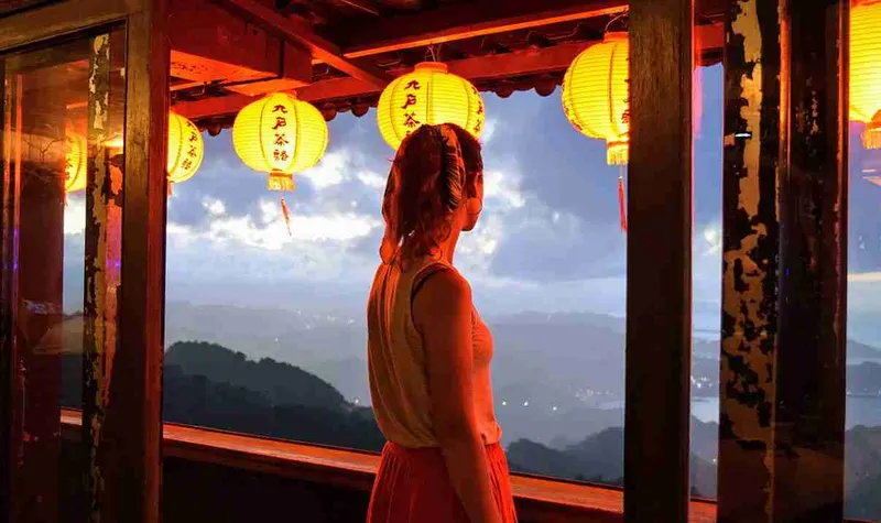 Mujer de rojo ante una pared de farolillos, en Jiufen