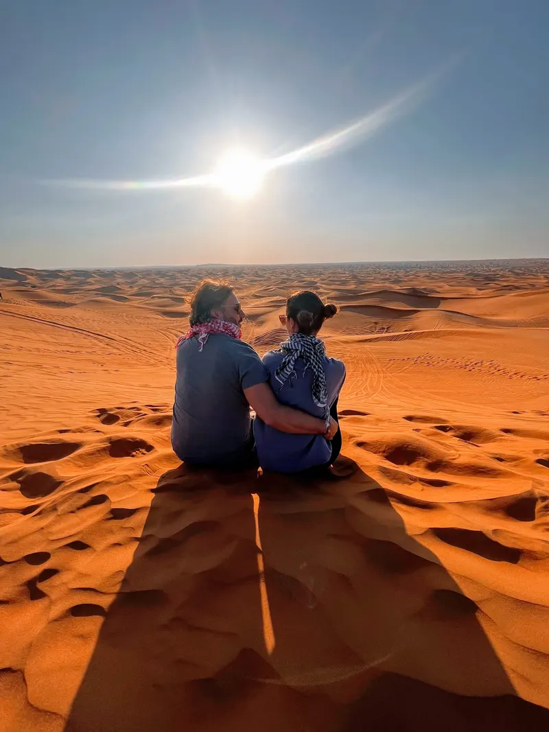 Pareja en las dunas del deiserto de Dubai al atardecer