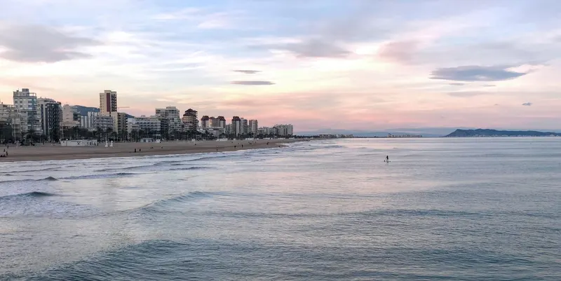 bonito atardecer en Gandia playa con chico haciendo paddlesurf