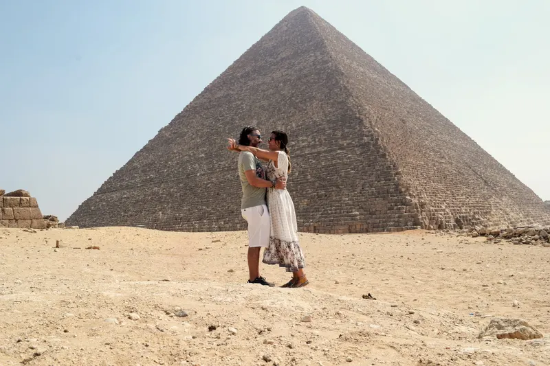 pareja ante una de las maravillas antiguas del mundo, la piramide de Keops, Egipto