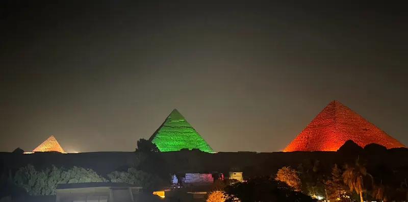Panoramica de las piramides de Giza iluminadas por la noche con diferentes colores, El Cairo, Egipto