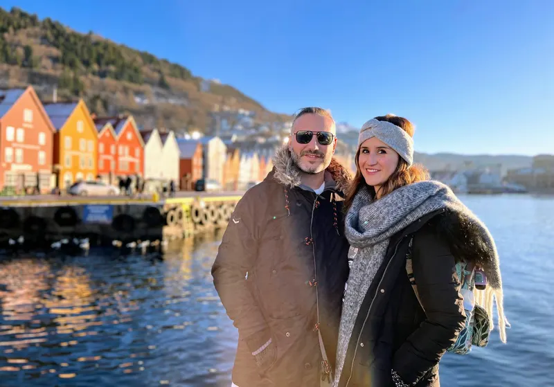 Pareja ante las casas de madera de colores del muelle de Bryggen, en Bergen