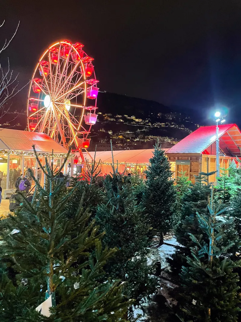 Mercado de Navidad de Bergen de noche, noria y tienda de abetos