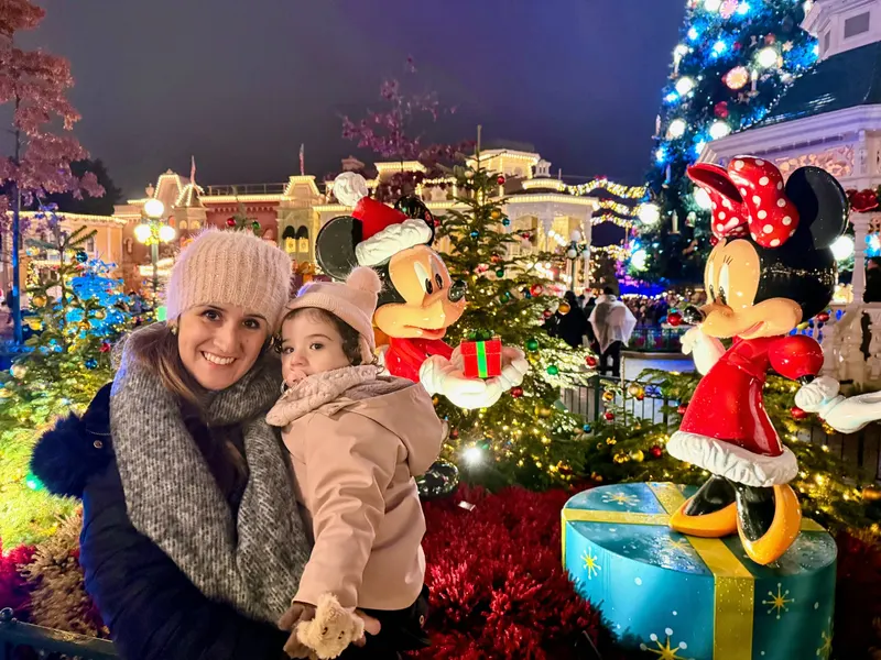 Madre e hija abrigadas junto al árbol de Navidad y las figuras de Mickey y Minnie en Main Street