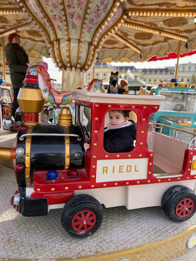 Nuestra hija en un tiovivo con forma de tren en un mercado navideño de Viena