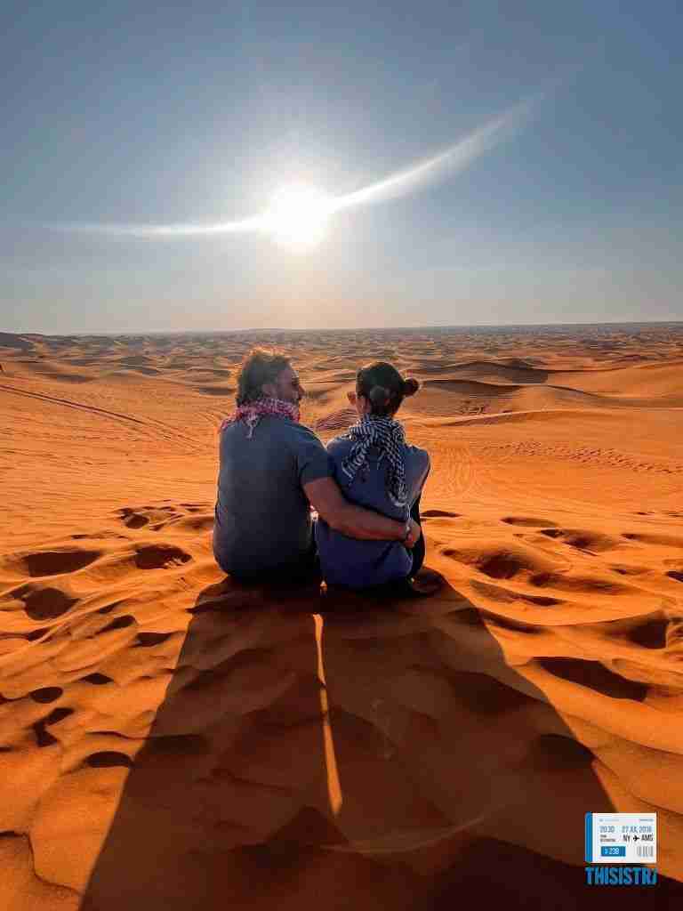 Pareja en las dunas del deiserto de Dubai al atardecer