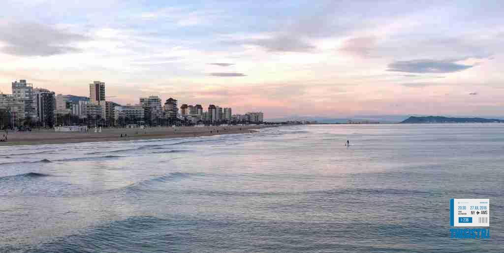 bonito atardecer en Gandia playa con chico haciendo paddlesurf